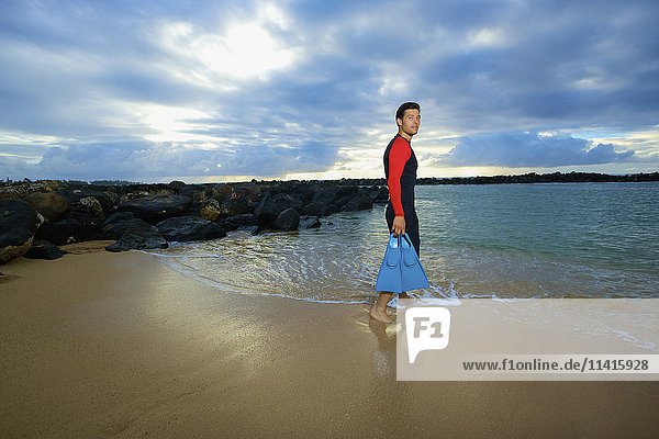 Ein Mann geht vom Lydgate Beach mit Schwimmflossen ins Wasser; Kauai  Hawaii  Vereinigte Staaten von Amerika'.