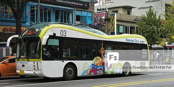 'City bus with colourful artwork of a skyline on the side; Seoul  South Korea'