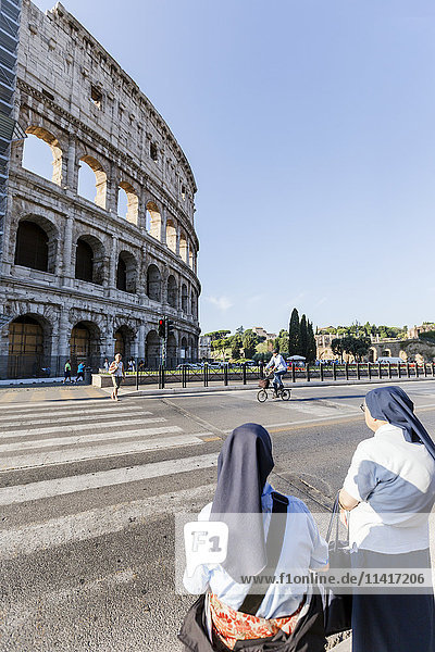 Ein Paar katholischer Nonnen wartet außerhalb der Vatikanstadt darauf  die Straße vor dem Kolosseum zu überqueren; Rom  Latium  Italien'.