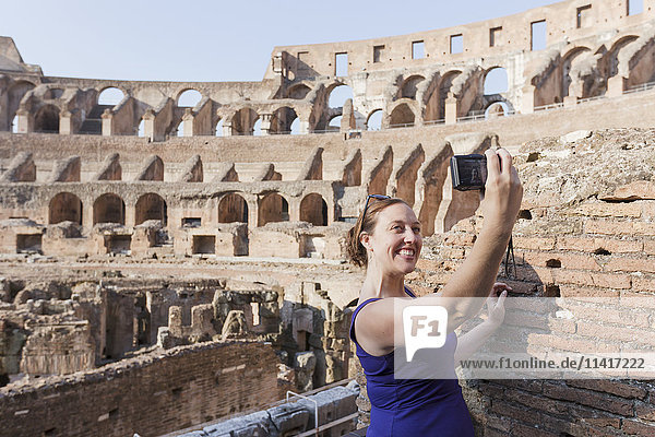 'A young female tourist takes a selfie with her camera at the Roman Colosseum; Rome Italy'
