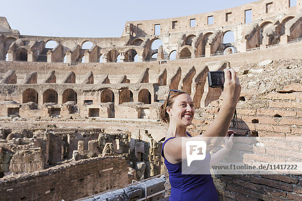 Eine junge Touristin macht ein Selfie mit ihrer Kamera im römischen Kolosseum; Rom  Italien'.