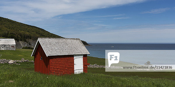 Ein kleiner roter Schuppen auf einem Grashügel mit Blick auf den Ozean; Capstick  Nova Scotia  Kanada .
