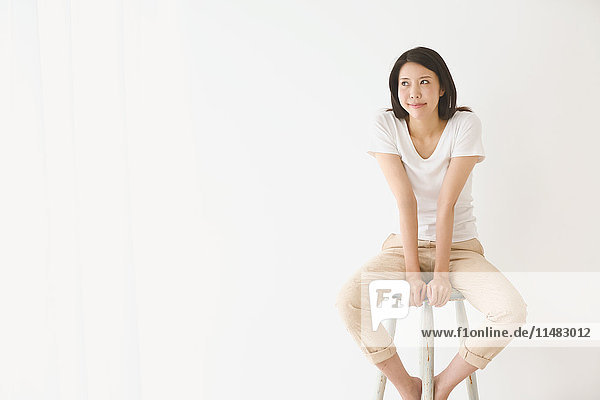 Young Japanese woman on a chair in a white room