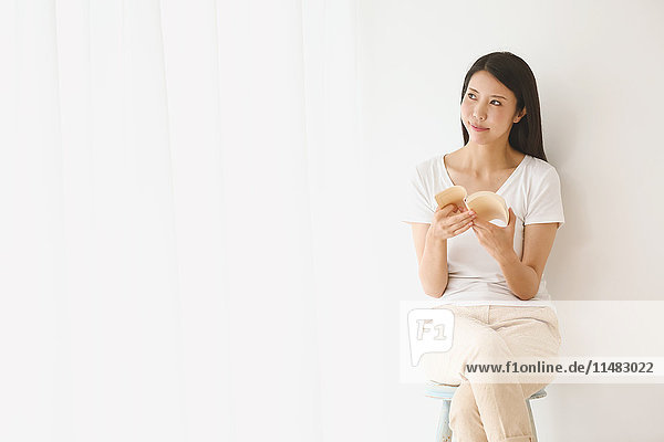 Junge japanische Frau auf einem Stuhl in einem weißen Raum