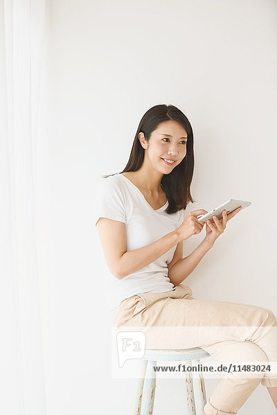 Young Japanese woman on a chair in a white room