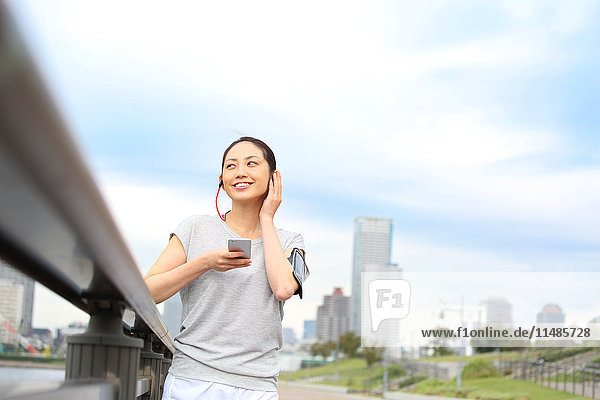 Attractive Japanese woman listening to music by a river downtown Tokyo  Japan
