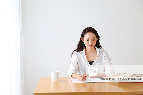 Attraktive japanische Frau sitzt an einem Tisch in einem luftigen Raum
