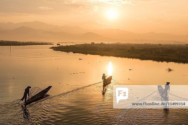Inle lake  Nyaungshwe township  Taunggyi district  Myanmar (Burma). Three local fishermen in silhouette at sunrise.