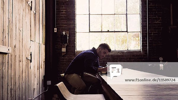 Young Adult Man with Steaming Cup of Coffee Writing in Journal