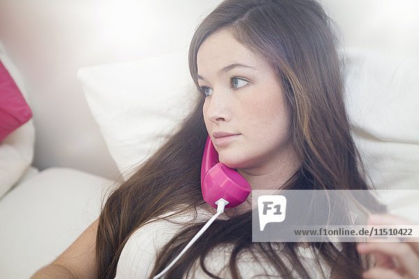 Junge Frau benutzt Telefon im Bett