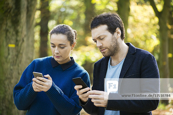 Paar überprüft Smartphones beim Waldspaziergang