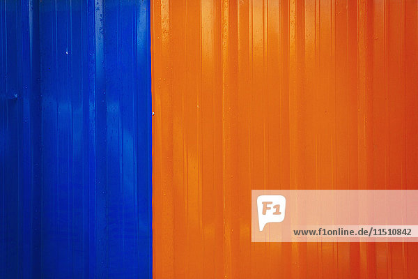 Eine glänzend bemalte Fläche an einer Wand  orange und blau gefärbt.