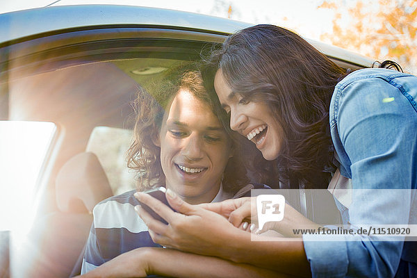 Paar sucht Wegbeschreibung auf dem Smartphone vor Fahrtantritt