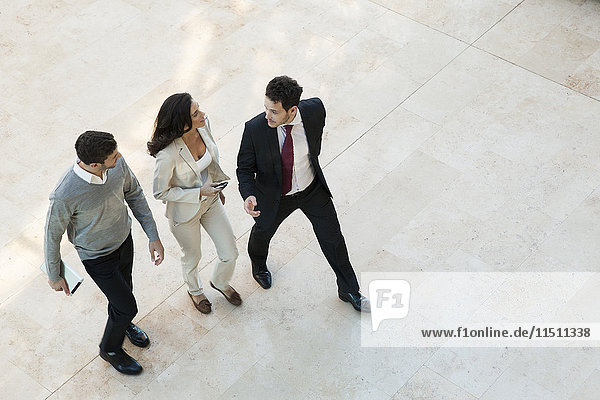 Business associates talking while walking together in office lobby
