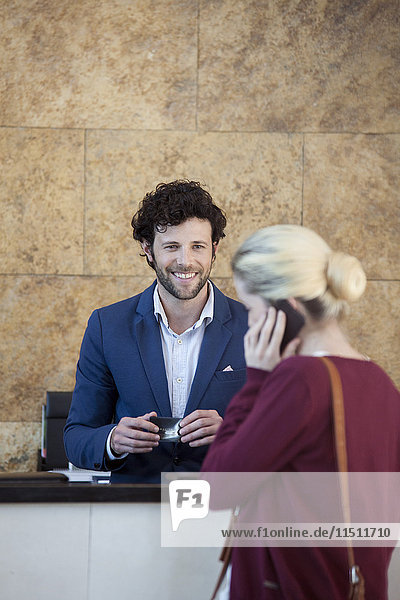 Friendly receptionist waiting to assist customer on cell phone