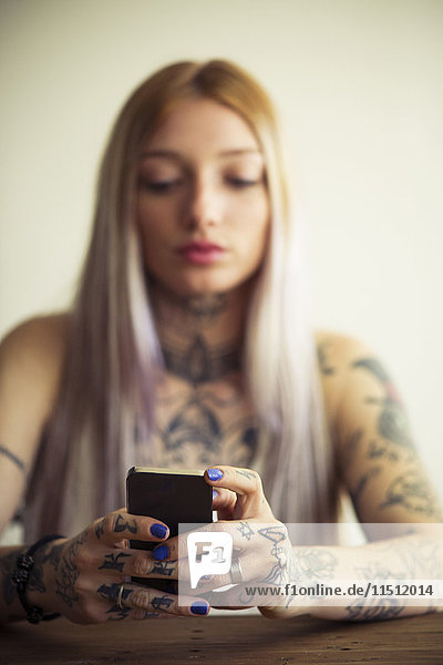 Tätowierte Frau mit Smartphone