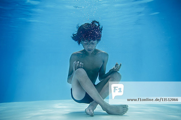 Boy resting in lotus position underwater