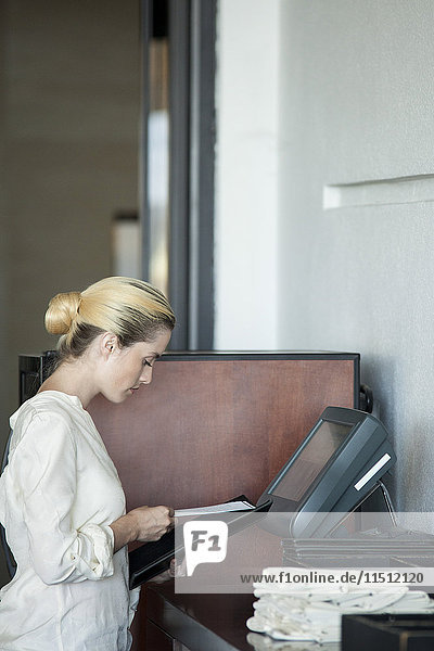 Kellnerin mit computergestützter Kasse im Restaurant
