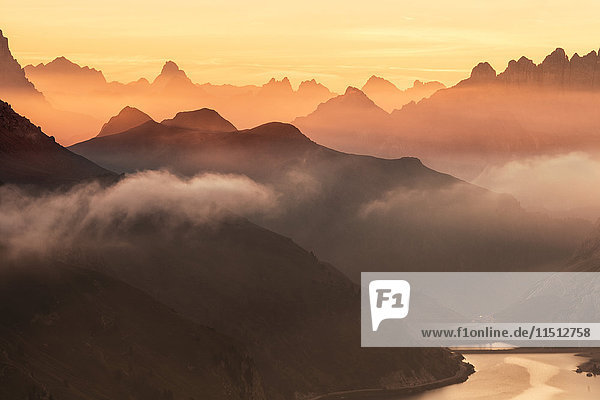 Orange sky at dawn and mist on peaks of Dolomites and Fedaia Pass Cima Belvedere Val di Fassa Trentino-Alto Adige Italy Europe