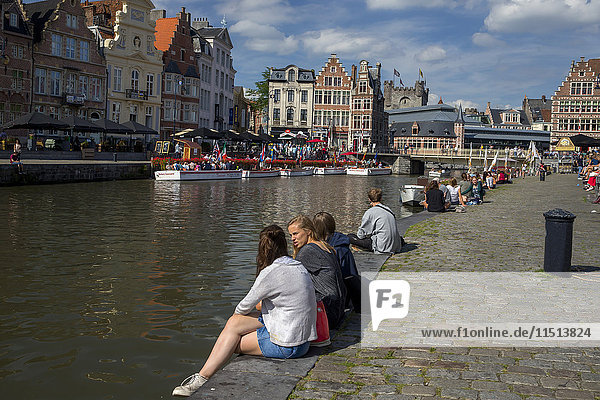 Young people enjoy summer sunshine along the Graslei and Korenlei  Ghent  Belgium  Europe