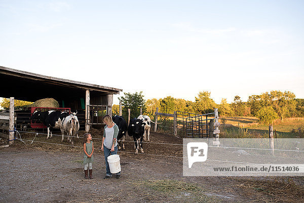 Mutter und Tochter stehen zusammen auf dem Bauernhof und halten Tierfutter