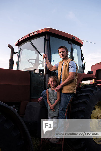 Portrait of father and daughter beside tractor