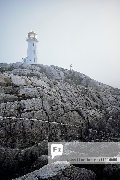 Couple on rocks by lighthouse  Peggy's Cove  Nova Scotia  Canada