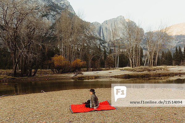 Frau sitzt auf einer roten Decke und schaut auf die Landschaft  Yosemite National Park  Kalifornien  USA