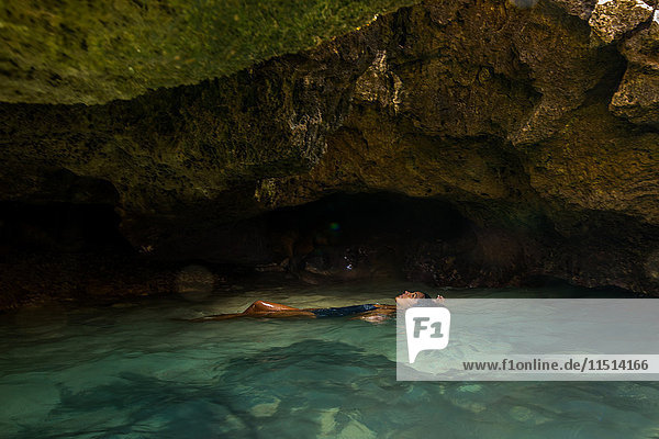 Woman floating in water filled cave  Oahu  Hawaii  USA