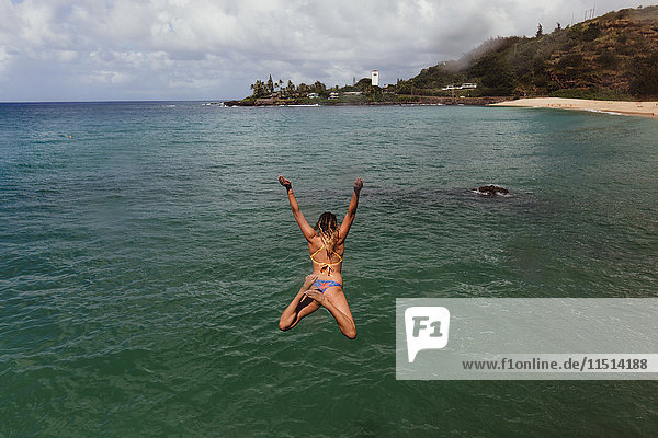Rückansicht einer Frau  die ins Meer springt  Oahu  Hawaii  USA