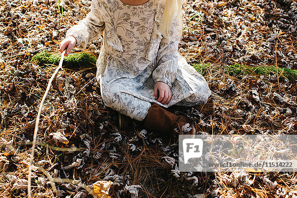 Mädchen hält Stock im Wald