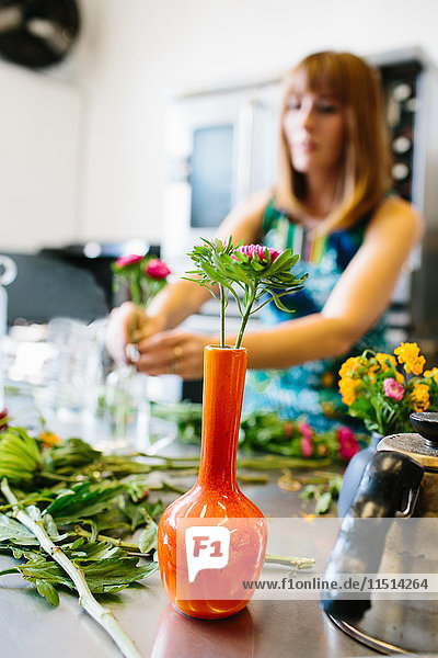 Frau arrangiert Blumen in Vase