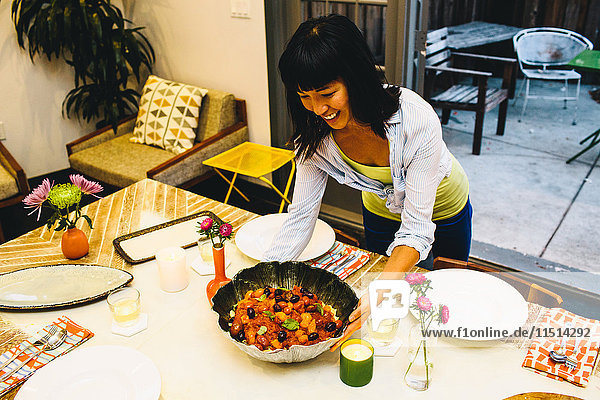 Woman placing dish on dining table