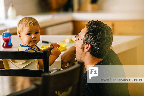 Vater hilft kleinem Sohn beim Essen