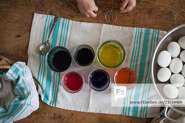 Draufsicht auf die Hände eines Mädchens  das sich bei Tisch darauf vorbereitet  Ostereier zu färben