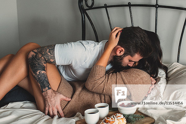 Leidenschaftliches junges Paar mit Frühstück im Bett