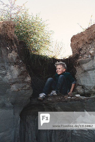 Junge versteckt sich auf Felsvorsprung unterhalb der Felskante