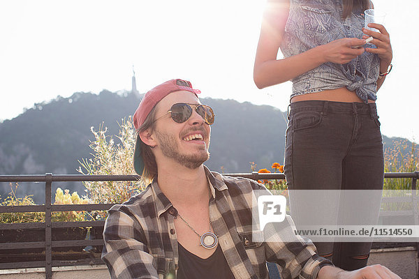 Happy young man at sunlit roof terrace party