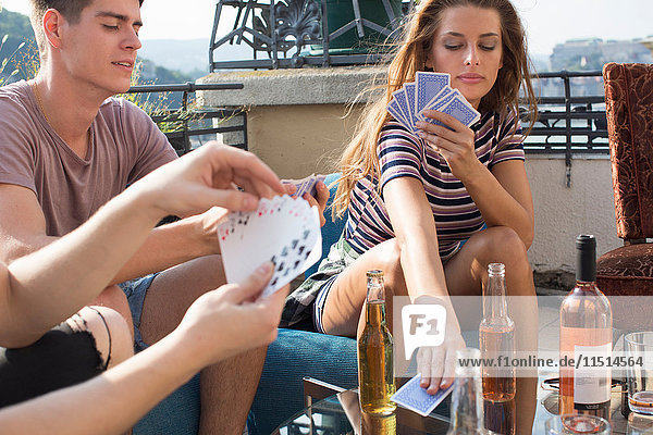 Junge erwachsene Freunde spielen Kartenspiele auf der Dachterrassenparty