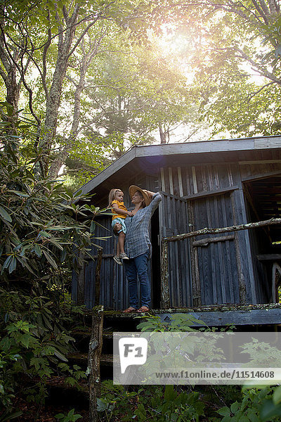 Mother and daughter standing outside wooden cabin