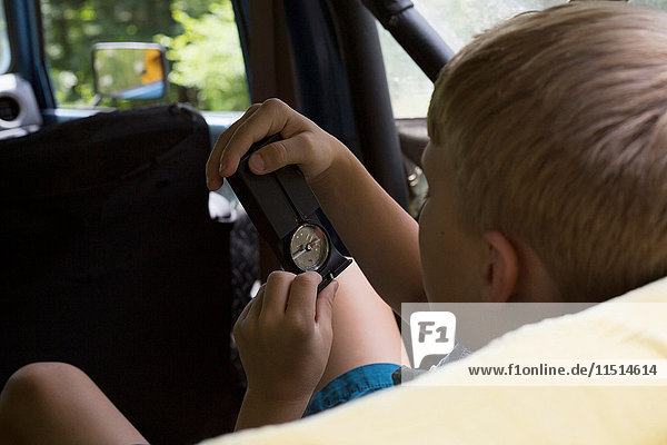 Junge auf dem Rücksitz eines Fahrzeugs  schaut auf den Kompass