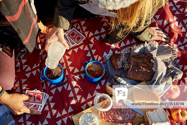 Overhead cropped view of couple pouring milk into coffee at picnic