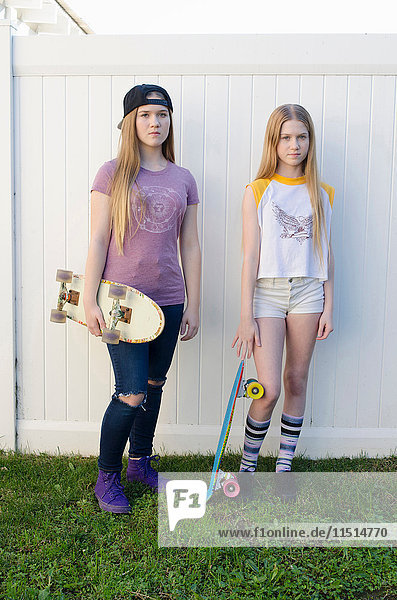 Porträt von zwei jugendlichen Skateboardfahrer-Schwestern im Garten