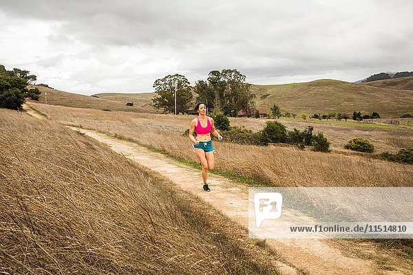 Female runner running on dirt track in landscape