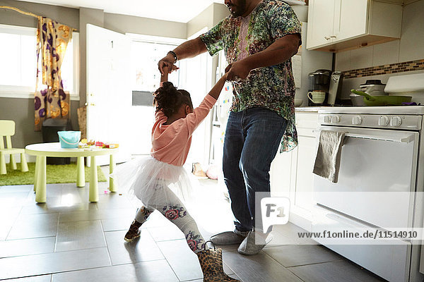 Father and daughter jiving in kitchen