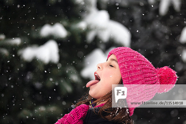 Mädchen fängt Schneeflocke auf der Zunge