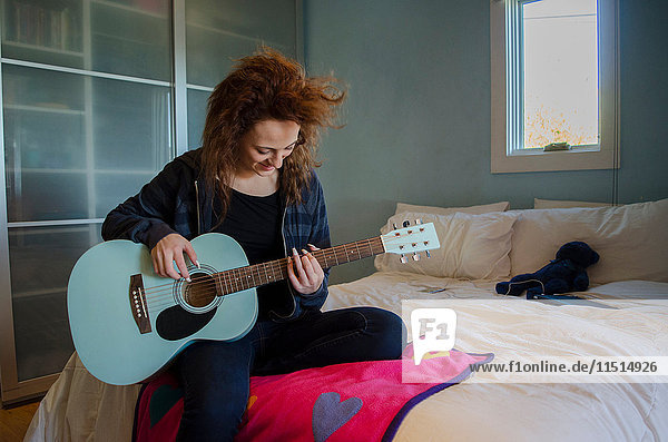 Teenager spielt Gitarre im Schlafzimmer