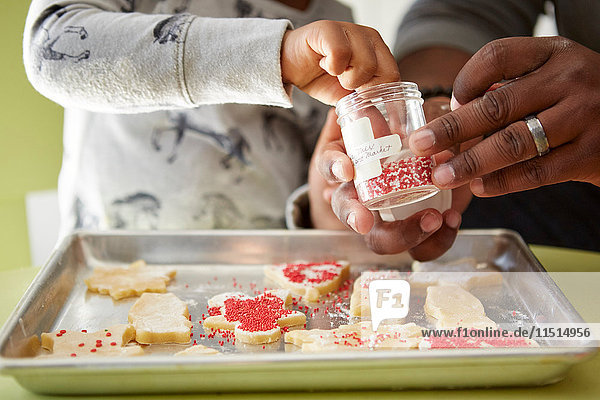Father and daughter decorating unbaked cookies  close-up