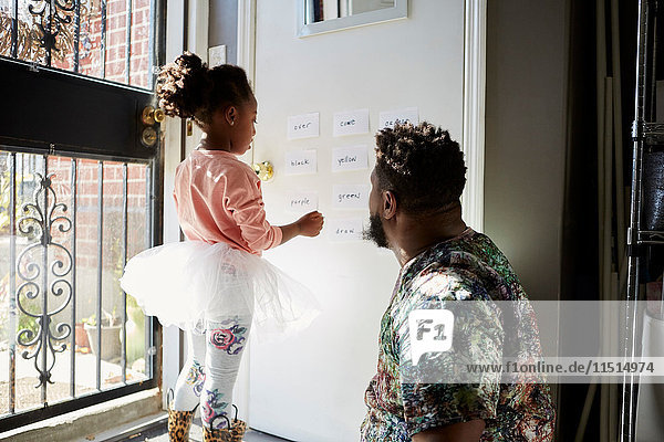 Girl in tutu with father reading words on wall