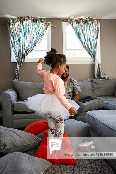 Girl in tutu dancing on cushions for father